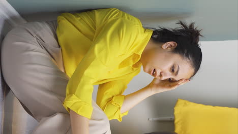 Vertical-video-of-The-young-woman-sitting-by-the-wall-is-angry-with-herself.